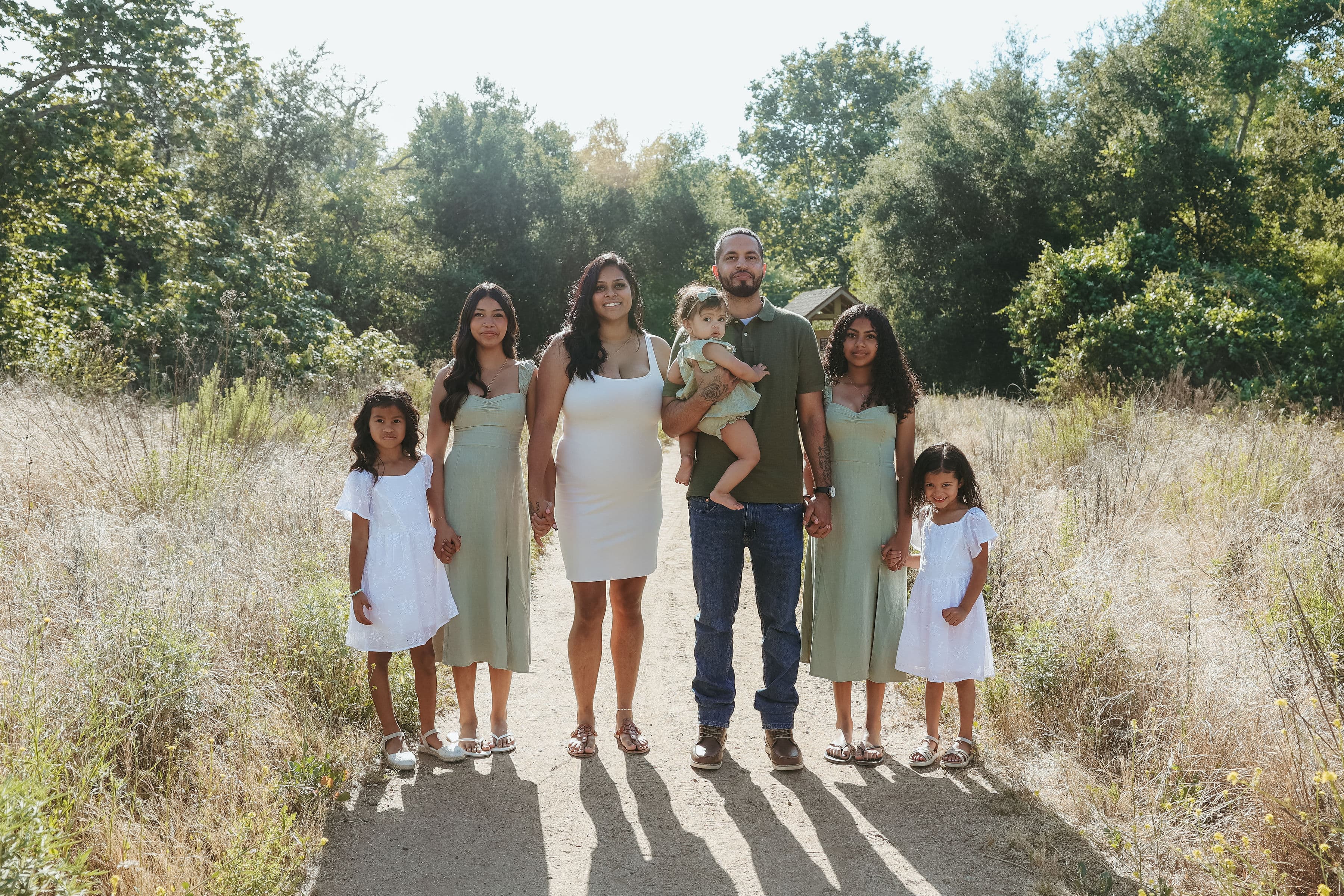 Jason and Jessika with their daughters on a tree-lined trail in San Diego