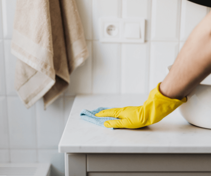 professional cleaner wearing yellow gloves hand wiping a countertop