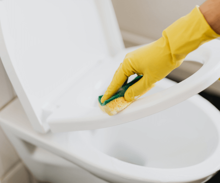 cleaner wearing yellow gloves hand wiping the toilet